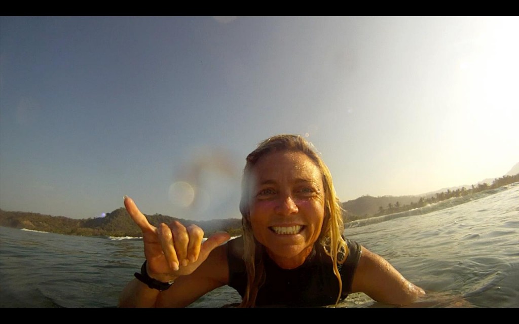 Jennifer Faith gives a hang ten from her surfboard to encourage battered women of all faiths