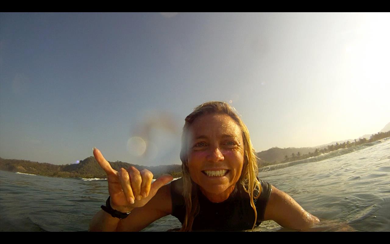 Jennifer Faith gives a hang ten from her surfboard to encourage battered women of all faiths